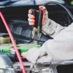 Car repairman wearing a white uniform standing and holding a wre