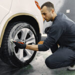 Male hand with foam sponge washing car